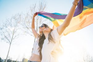 Couple lesbian woman with gay pride flag on the street